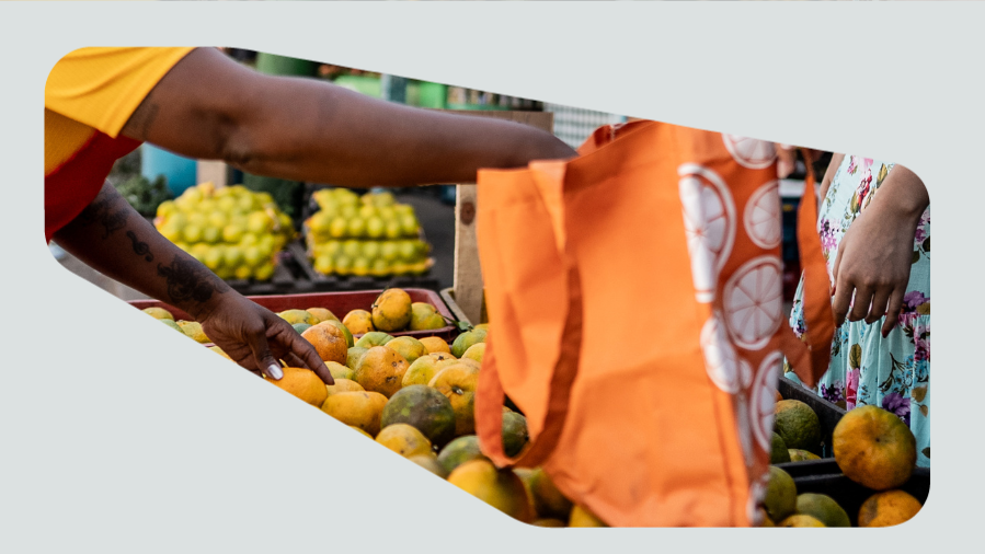 feirante com sacola de feira selecionando laranjas