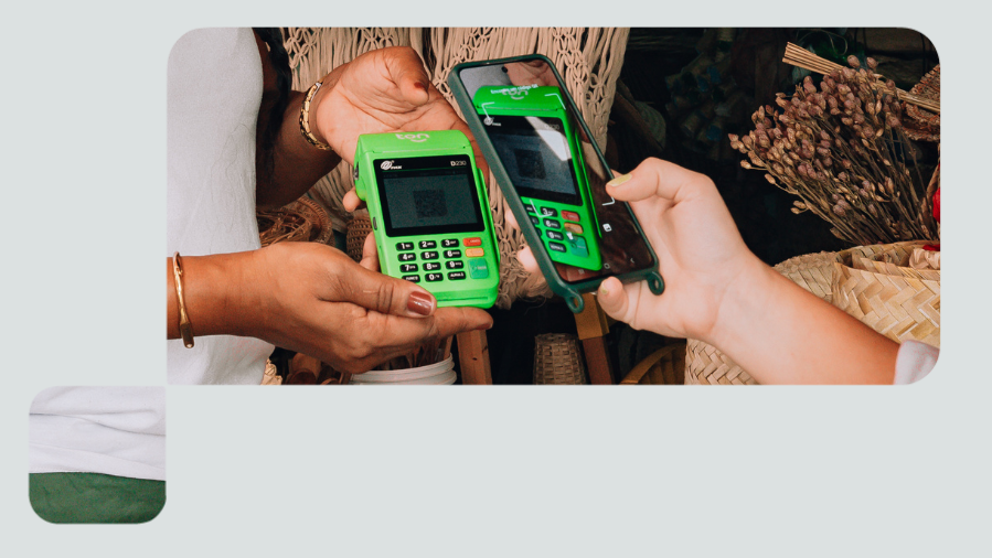 foto detalhe das mãos de duas pessoas, uma segurando maquininha de cartão e a outra, pagando com celular por aproximação