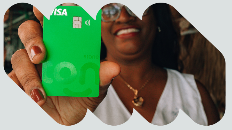 mulher negra sorrindo e segurando um cartão ton