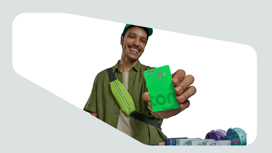 vendedor ambulante sorrindo e segurando cartão de crédito verde do ton