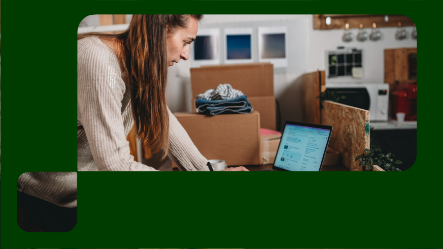 mulher em pé digitando notebook com caixas de papelão ao fundo